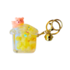 A cute yellow liquid-filled house keychain with floating beads, featuring a small bear figure on top, attached to a gold keyring.