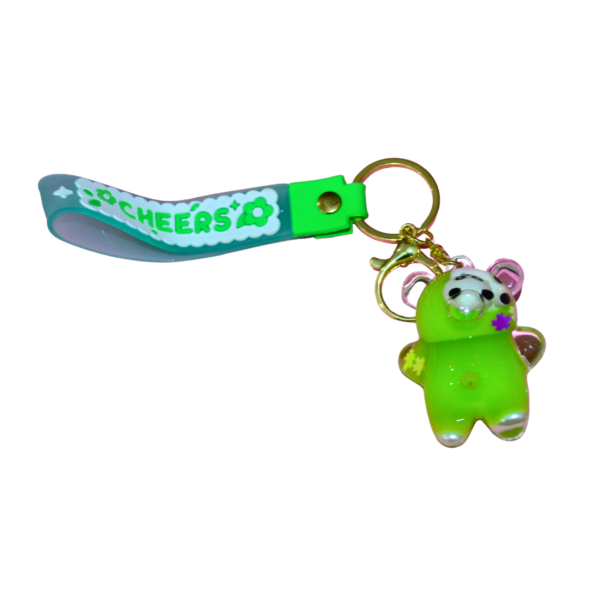 A green glitter-infused resin bear keychain with a panda face, attached to a gold keyring and a green "CHEERS" silicone strap.